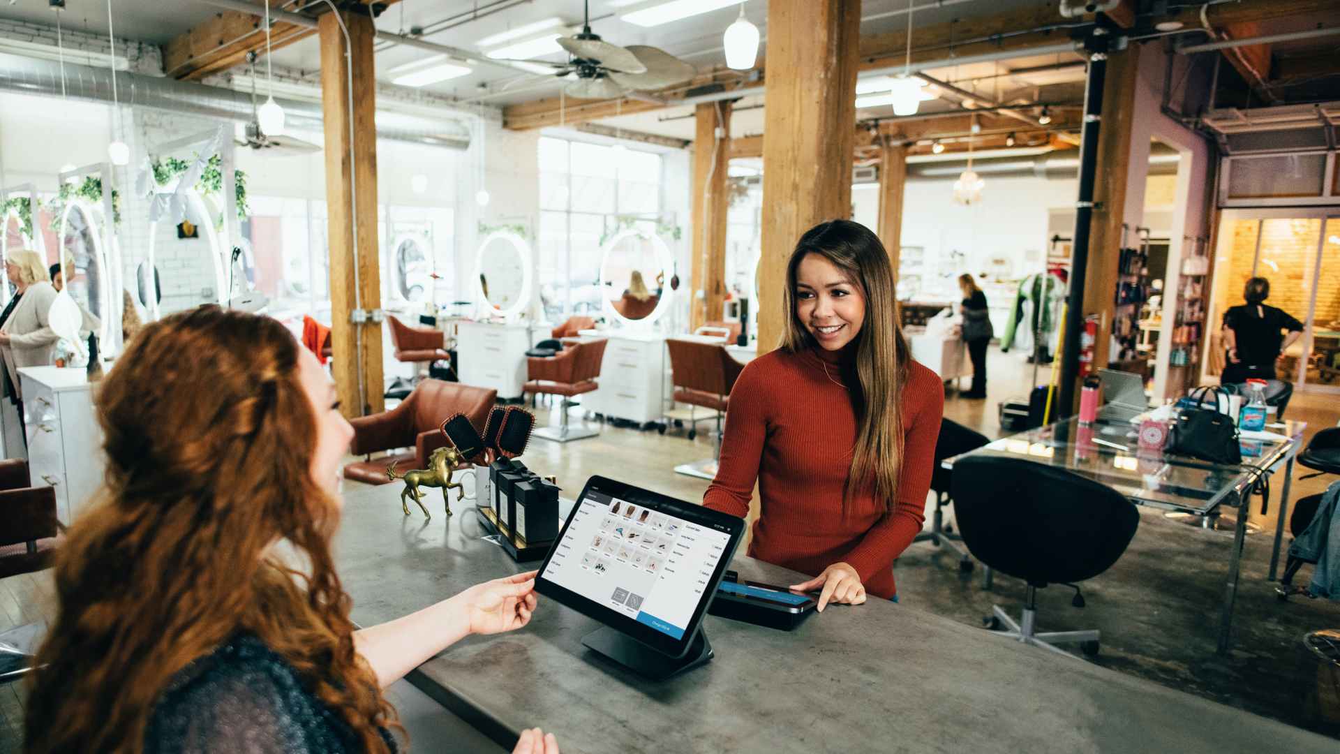 Two ladies with one handing a paper over the counter