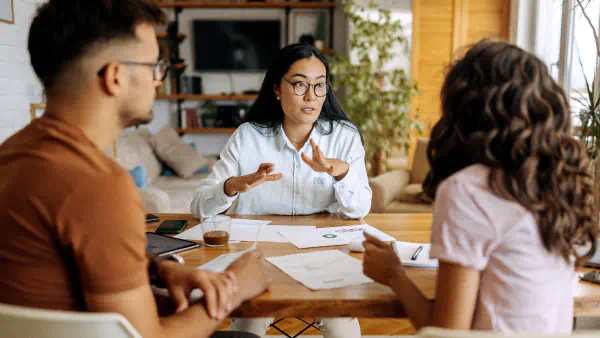 Woman sitting at desk discusses coverage with a seated couple